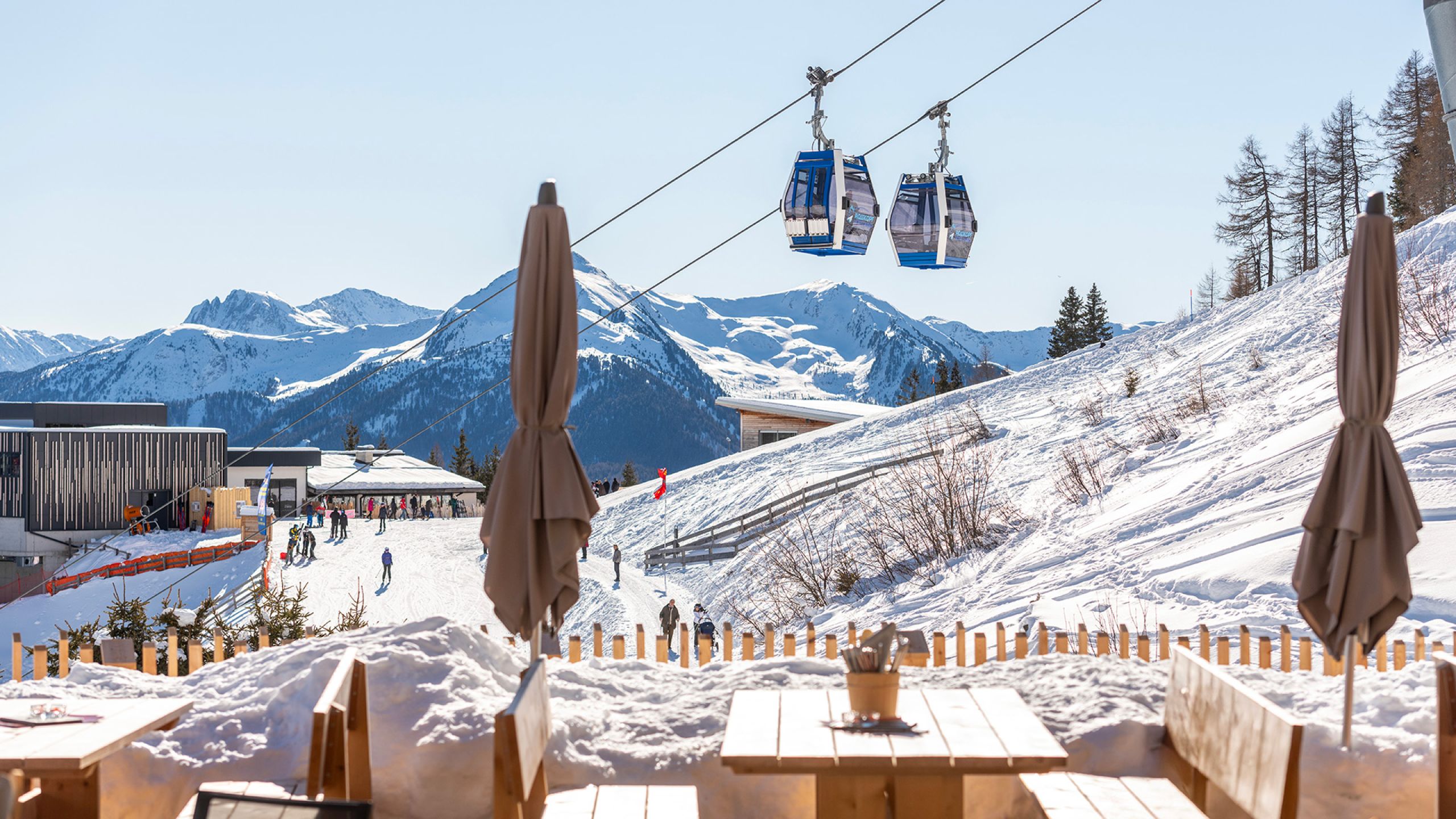 Blick von der Terrasse des Alpin Chalet Rosskopf auf die Kabinenbahn Monte Cavallo und die verschneiten Berge oberhalb von Vipiteno