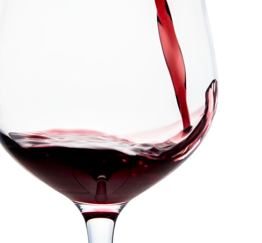 Rotwein in ein Glas gegossen, mit Bewegung des Weins im Glas auf hellem Hintergrund