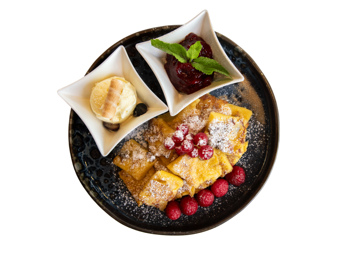 Kaiserschmarrn mit Puderzucker und roten Früchten, serviert mit Vanilleeis und Pflaumenkompott auf einem Gourmet-Teller