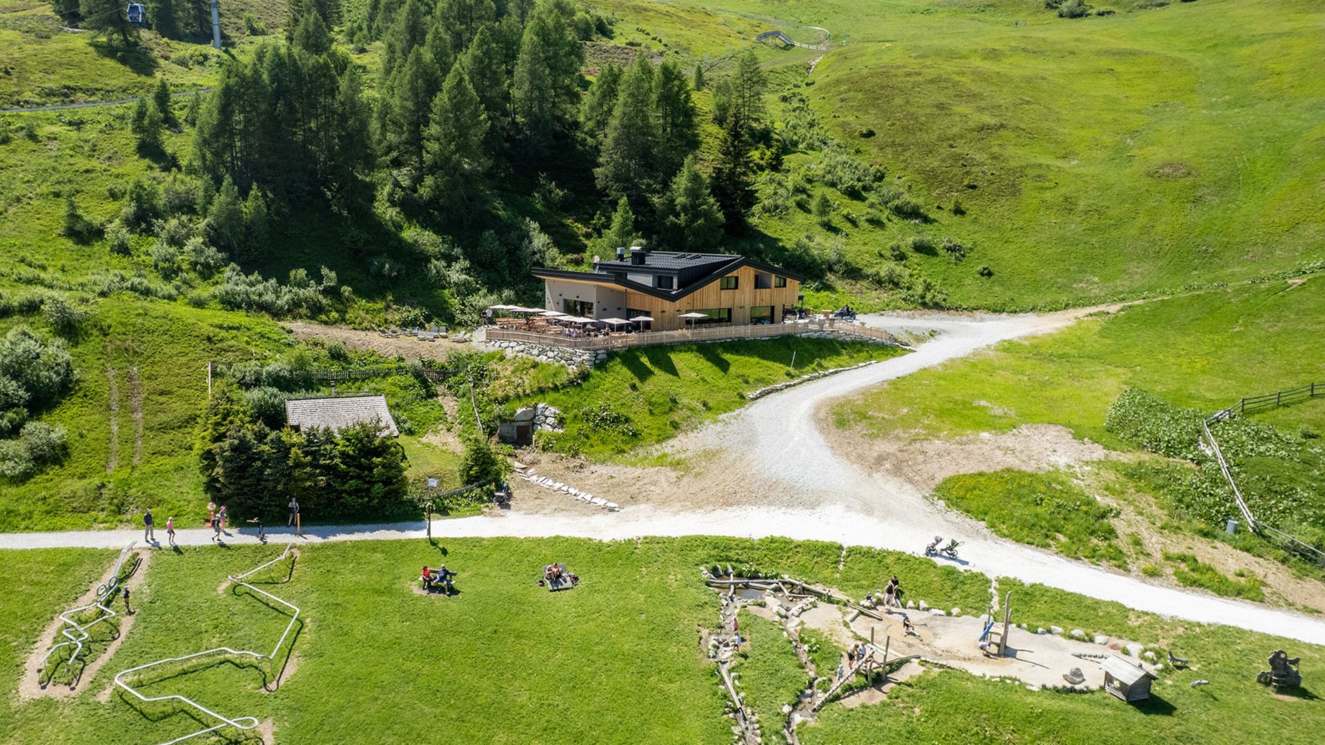 Luftaufnahme des Alpin Chalet Rosskopf inmitten grüner Bergwiesen.	