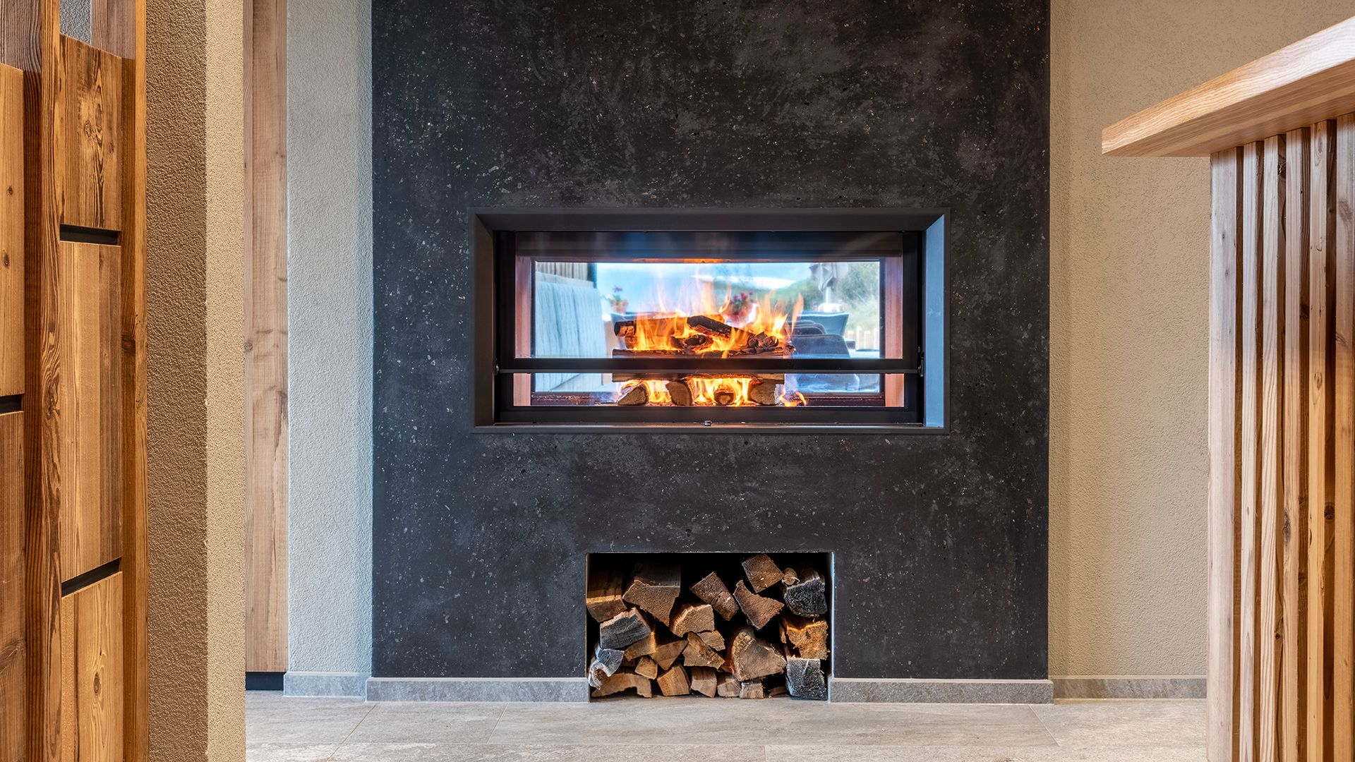 Moderner Kamin mit brennendem Feuer in alpinem Ambiente.	